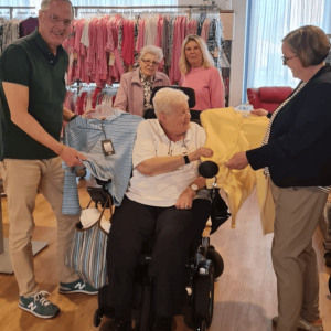 Bewohnerinnen und Mitarbeitende präsentieren ausgewählte Kleidungsstücke beim Besuch des Modemobils im Veronika-Haus