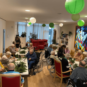Bewohnerinnen und Bewohner im Franziskus-Haus Kleve binden gemeinsam Palmzweige in geselliger Runde.
