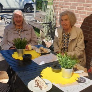Drei Frauen sitzen an einem Tisch mit Kuchen.