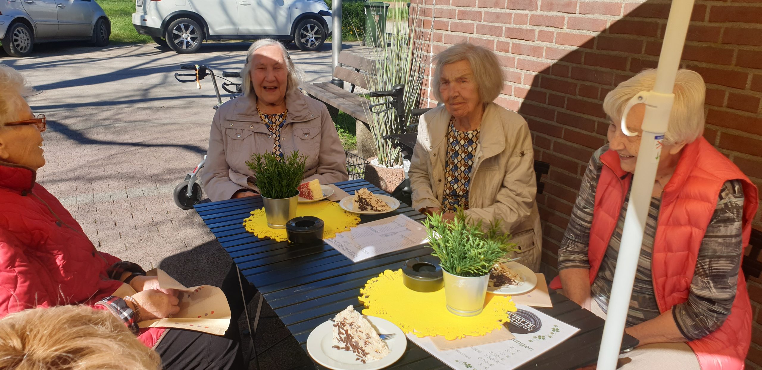 Drei Frauen sitzen an einem Tisch mit Kuchen.