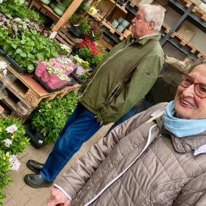 Seniorin und Senior wählen gemeinsam blühende Pflanzen in einem Gartencenter aus.