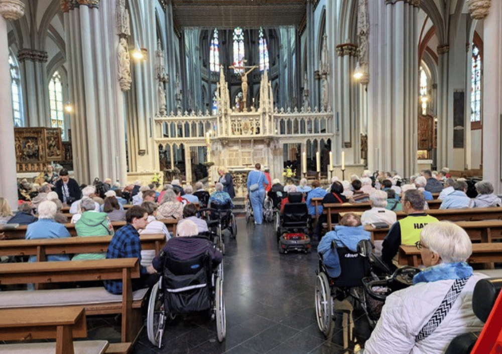 Teilnehmende der Domwallfahrt aus dem St. Elisabeth-Haus Xanten während der Messe im Xantener Dom, viele Personen sitzen in den Kirchenbänken und im Rollstuhl vor dem Altar