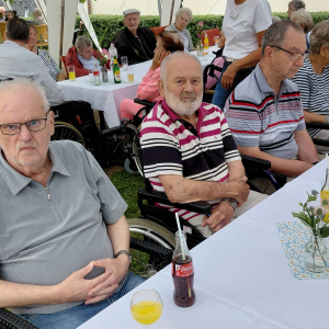 Bewohner sitzen gemeinsam an einem festlich gedeckten Tisch beim Sommerfest.