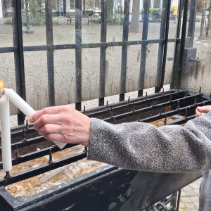 Seniorin stellt eine brennende Kerze in einem Kerzenständer auf.