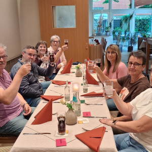Kleine Gruppe beim Abendessen und Anstoßen im Restaurant.