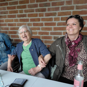 Drei Frauen sitzen gemeinsam am Tisch und genießen das Sommerfest im Innenhof.