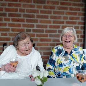 Zwei Bewohnerinnen stoßen mit einem Glas Rosé auf das Sommerfest an.
