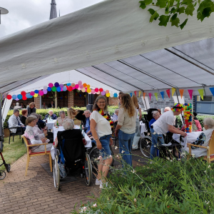 Sommerfest im Innenhof mit Bewohnerinnen, Bewohnern und Mitarbeitenden unter einem festlich geschmückten Pavillon.