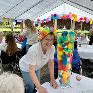 Mitarbeiterin präsentiert ein buntes Spiel mit verschiedenen Bällen beim Sommerfest.