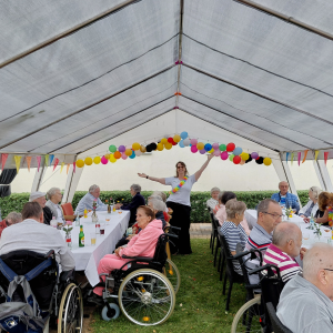 Bewohner sitzen gemeinsam an einem festlich gedeckten Tisch beim Sommerfest.