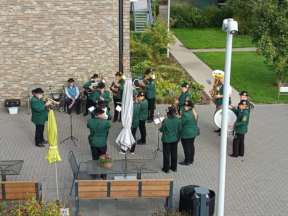 Eine Blaskapelle in grünen Uniformen spielt im Innenhof, aufgenommen aus erhöhter Perspektive.
