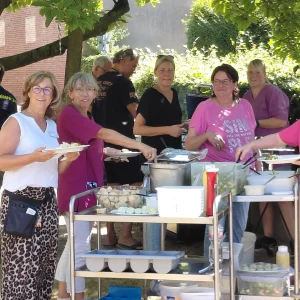 Mitarbeitende bereiten gemeinsam das Essen vor und geben die Speisen am Buffet aus.