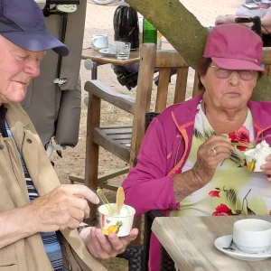 Ein älterer Mann und eine ältere Frau sitzen im Freien und essen Eis aus kleinen Bechern.