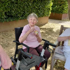 Eine Bewohnerin sitzt im Garten und genießt ihr Eis.