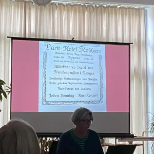 Vortrag zur Geschichte des Forstgartens in Kleve mit historischer Werbung für das Park-Hotel Robbers auf der Leinwand.