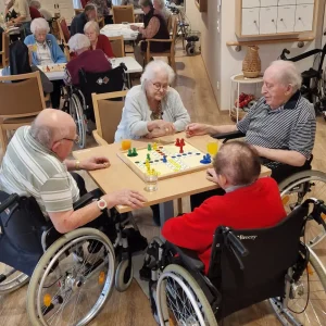 Vier ältere Menschen spielen Mensch ärgere dich nicht