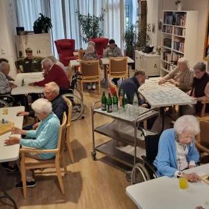 Mehrere Gruppen spielen an Tischen Brett- und Legespiele.