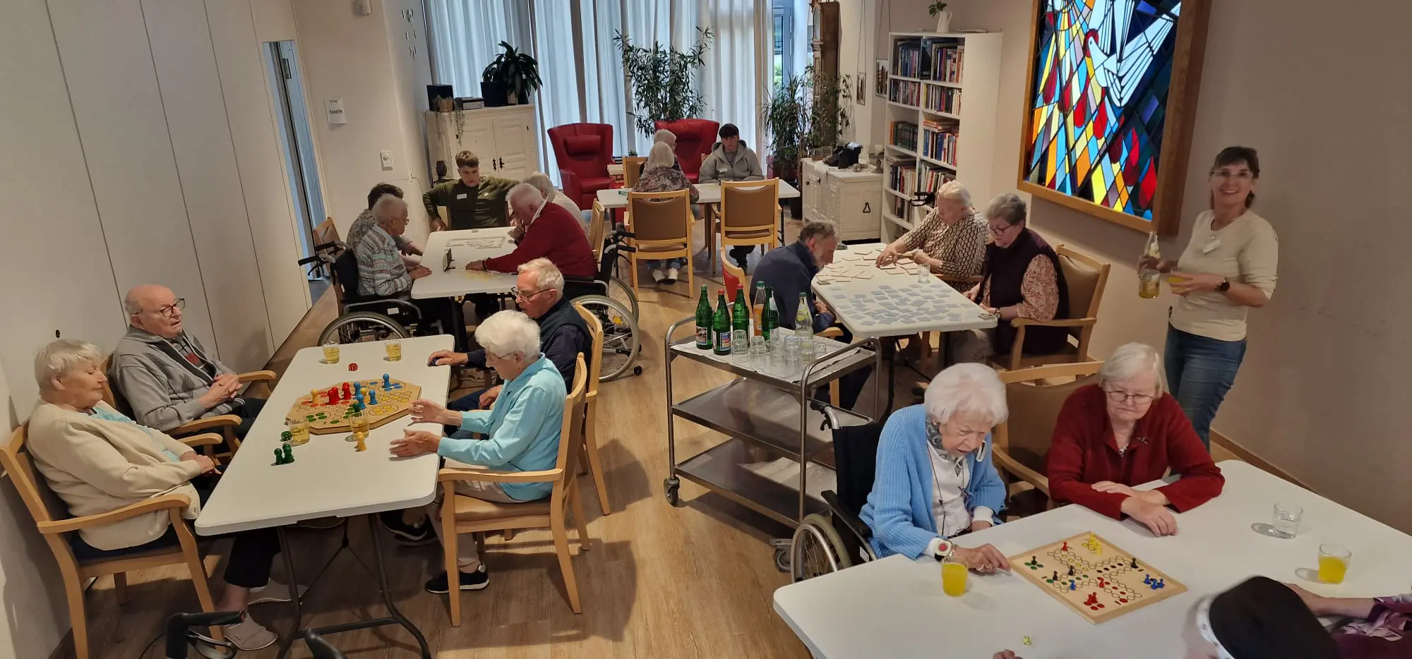 Spielen in Gemeinschaft Mehrere Gruppen spielen an Tischen Brett- und Legespiele.