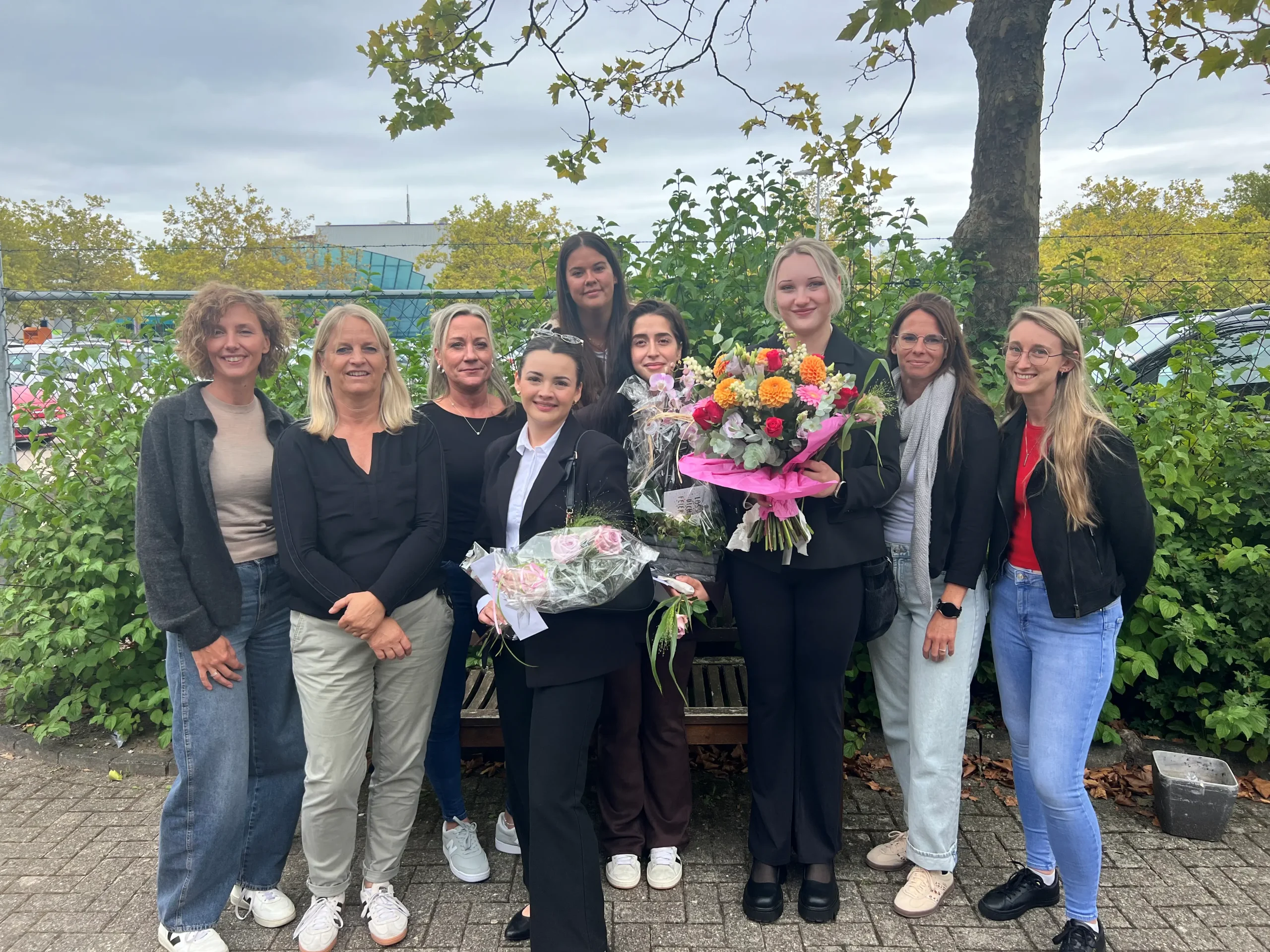 Das Team feiert gemeinsam einen besonderen Anlass und überreicht Blumen als Zeichen der Anerkennung.