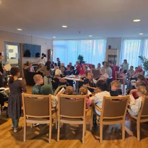 Kinder, Senioren und Betreuungskräfte treffen sich zu einem gemeinsamen Spielenachmittag im Gemeinschaftsraum.