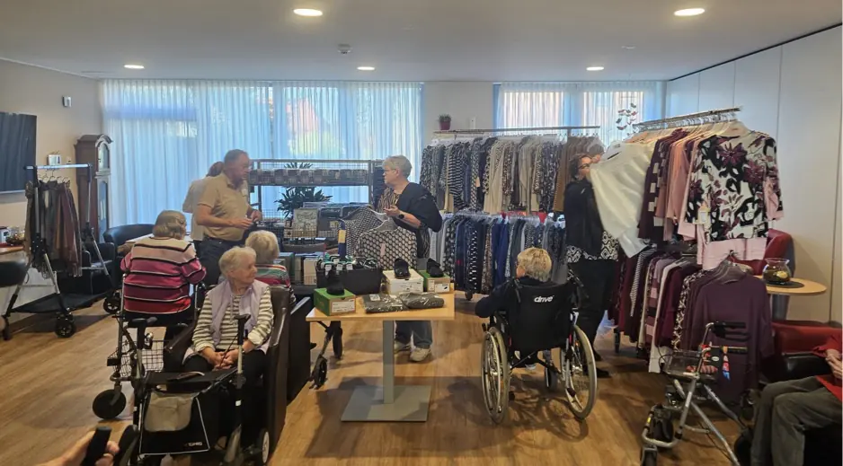 Mobiler Modeverkauf im Seniorenheim Seniorinnen und Senioren stöbern beim mobilen Modeverkauf zwischen Kleiderständern mit Hosen, Blusen und Pullovern.
