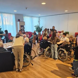 Kinder und ältere Menschen sitzen an mehreren Tischen und spielen gemeinsam Gesellschaftsspiele im Seniorenheim.