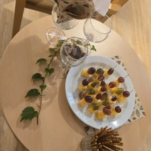 Käsespieße mit Trauben und Gurken liegen neben Salzstangen und Gläsern auf einem herbstlich dekorierten Tisch.