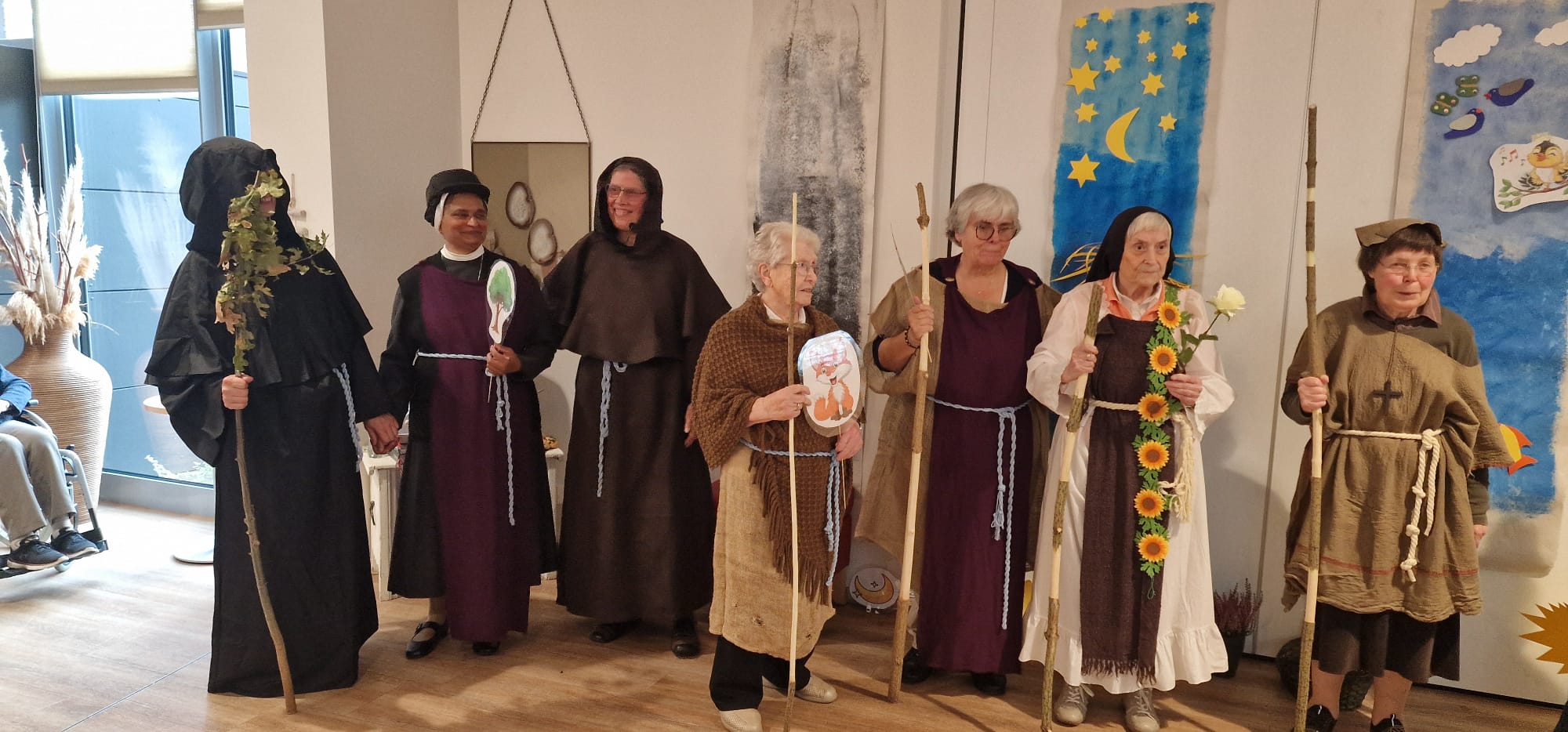 Theatergruppe präsentiert ihre Kostüme und Requisiten Sieben Darstellerinnen stehen in Kostümen mit Stäben und selbst gebastelten Tiermotiven vor einer Theaterkulisse.