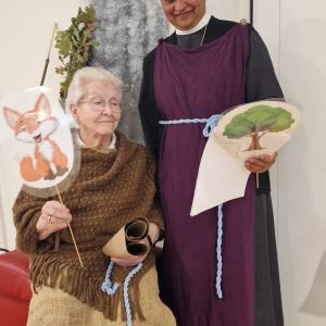 Eine Seniorin hält eine gebastelte Fuchsfigur, während eine Ordensschwester neben ihr eine Baumfigur präsentiert.